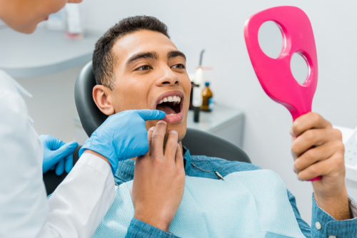 man looking at his smile at dental office